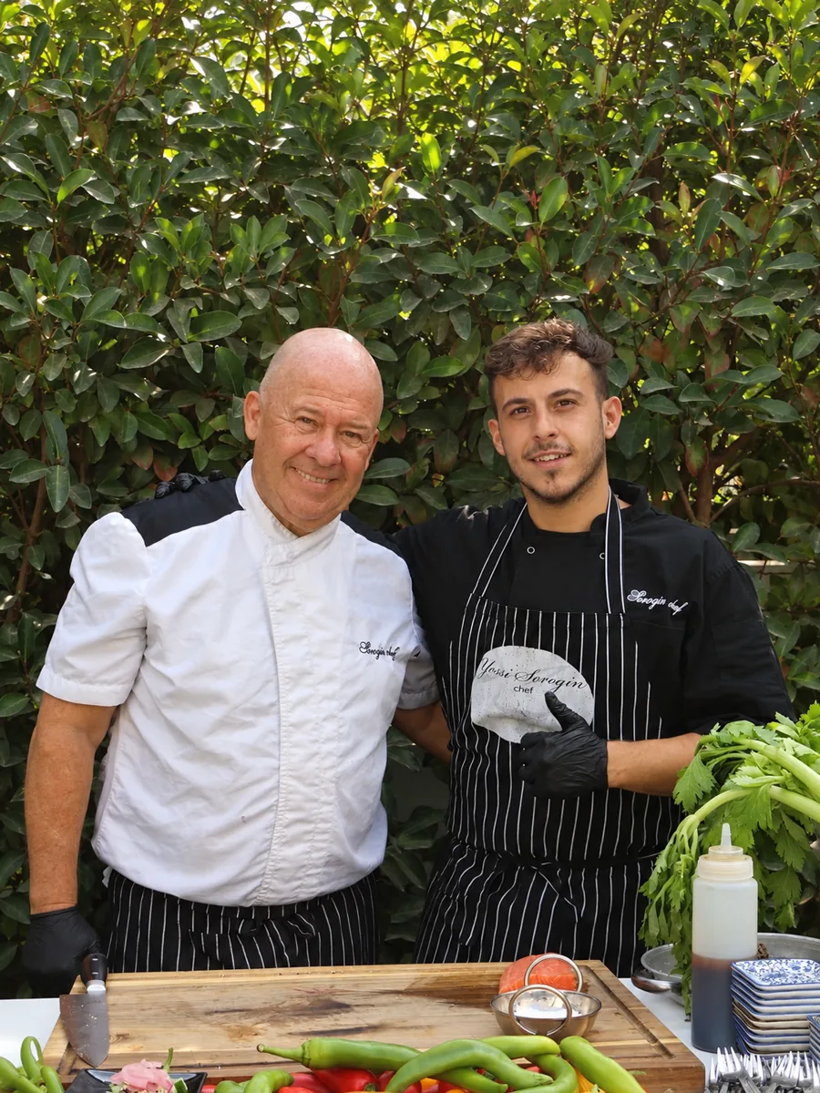 השפים של Sorozin Chef מאחורי קרש חיתוך ושולחן עמוס ירקות טריים
